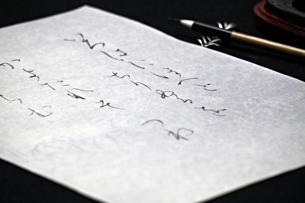 Student practicing Japanese calligraphy with brush and ink