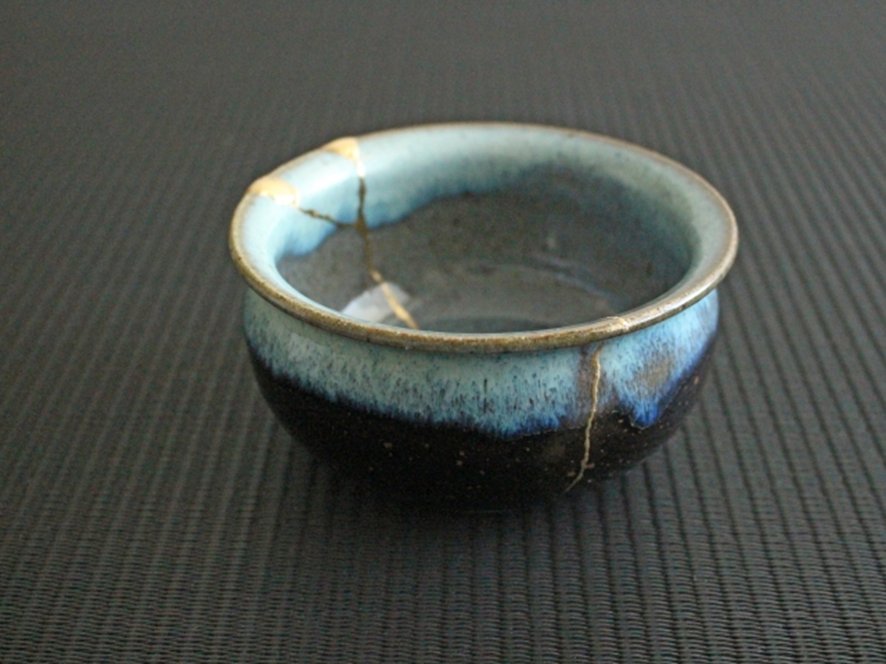 Hands applying gold powder to a ceramic piece at a kintsugi workshop in Tokyo