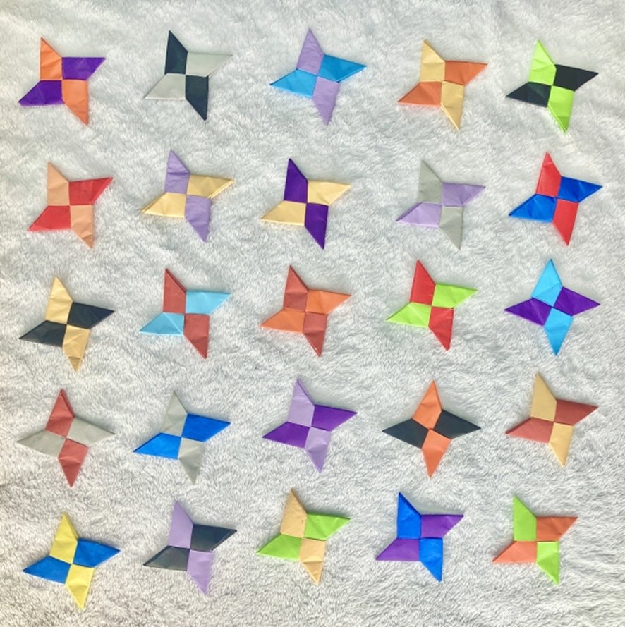 Hands folding colorful origami paper at a workshop table