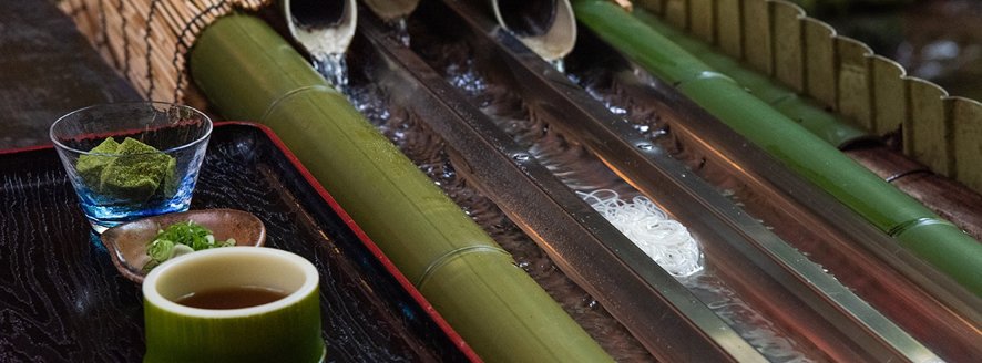 Somen noodles flowing in bamboo flume at riverside dining platform in Kibune